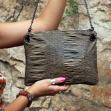 Someone holding the Distressed Black and Tan Bengal Stripe Crossbody Bag in front of a stone wall.