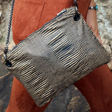 Someone wearing the Distressed Black and Tan Bengal Stripe Crossbody Bag with a burnt orange pants.