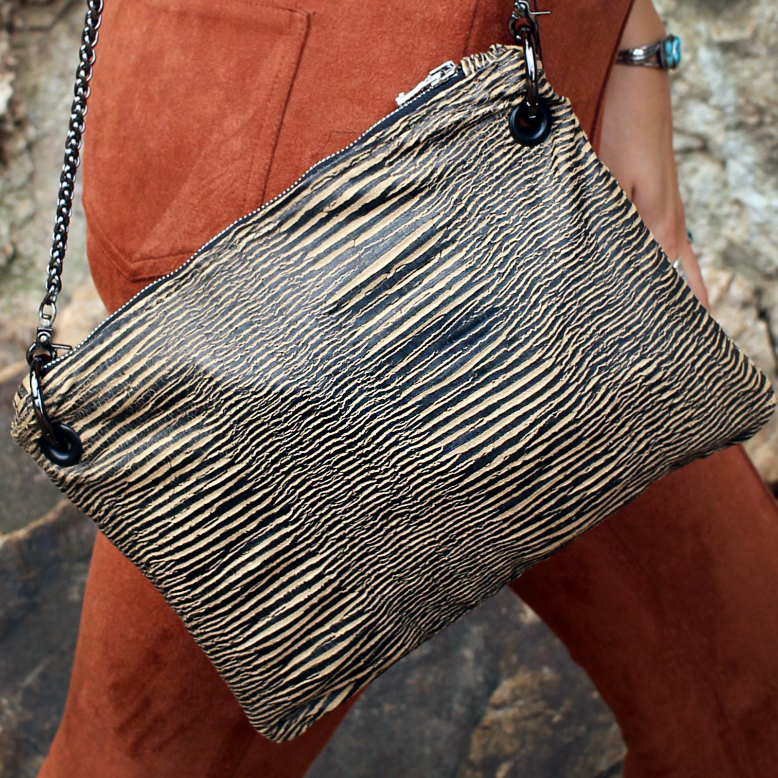 Someone wearing the Distressed Black and Tan Bengal Stripe Crossbody Bag with a burnt orange pants.